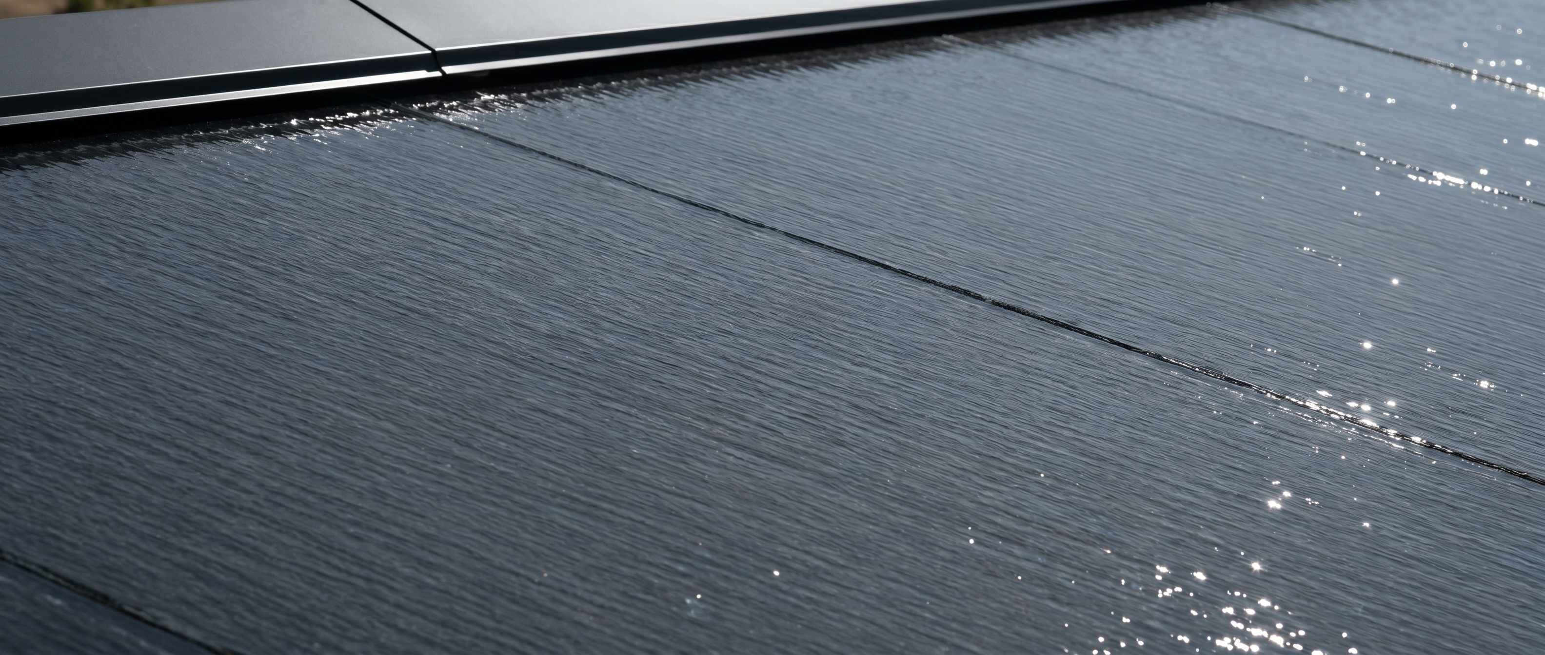 Close-up of a Tesla Solar Roof V3 textured glass tile field at solar noon, El Dorado Hills.
